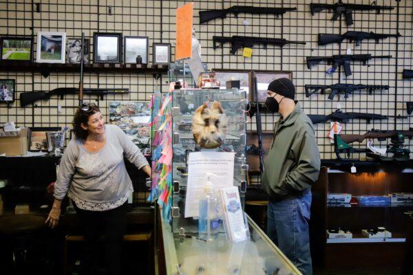 a person talks with a customer inside a gun store